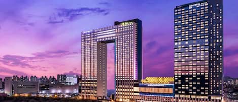 A modern hotel with a distinctive arch structure, multiple floors, and illuminated signage.