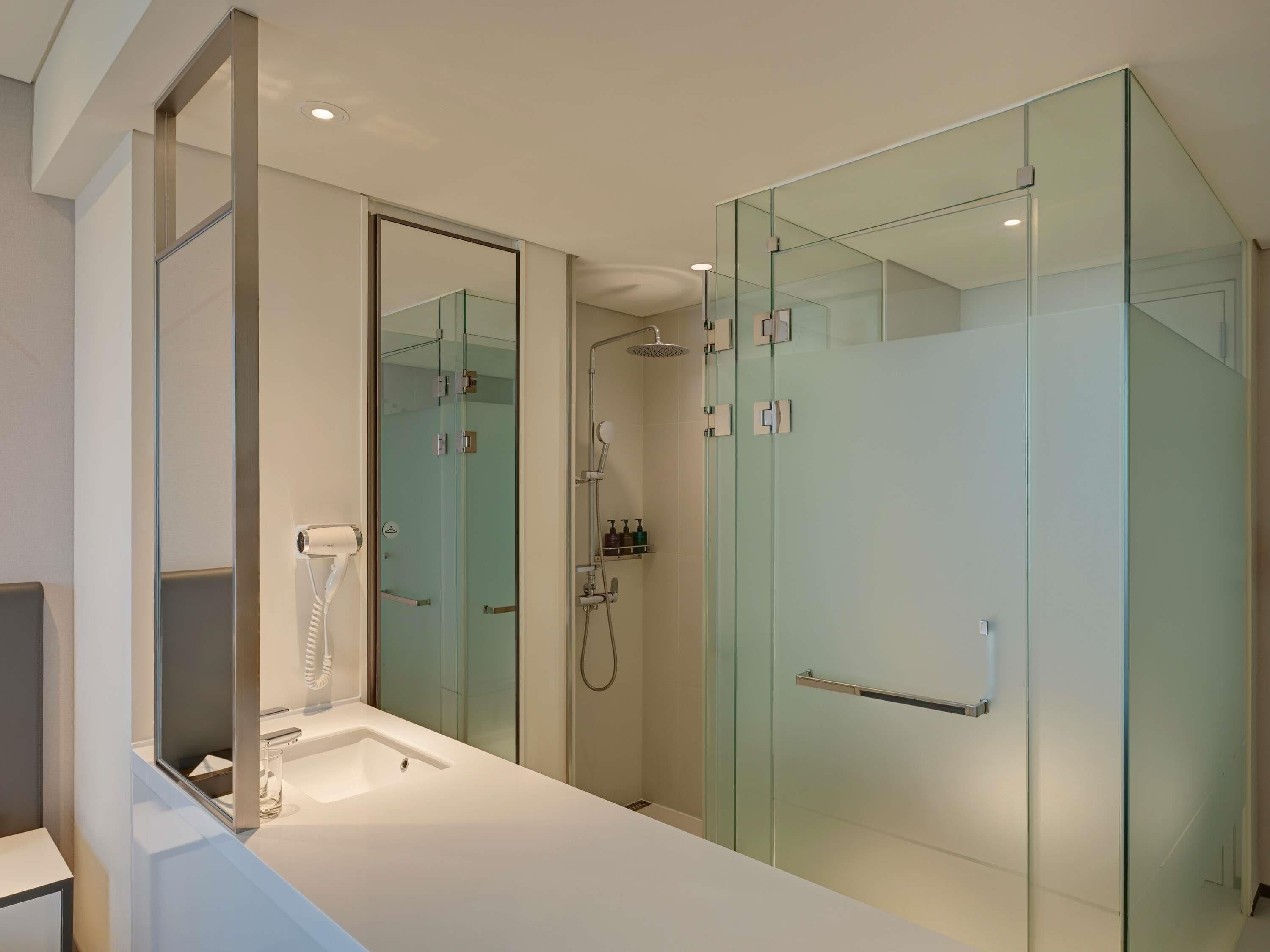 Un baño moderno con cabina de ducha de vidrio, lavabo empotrado y secador de pelo.