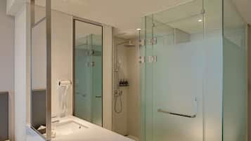 A modern bathroom with a glass shower enclosure, a built-in sink, and a hairdryer.