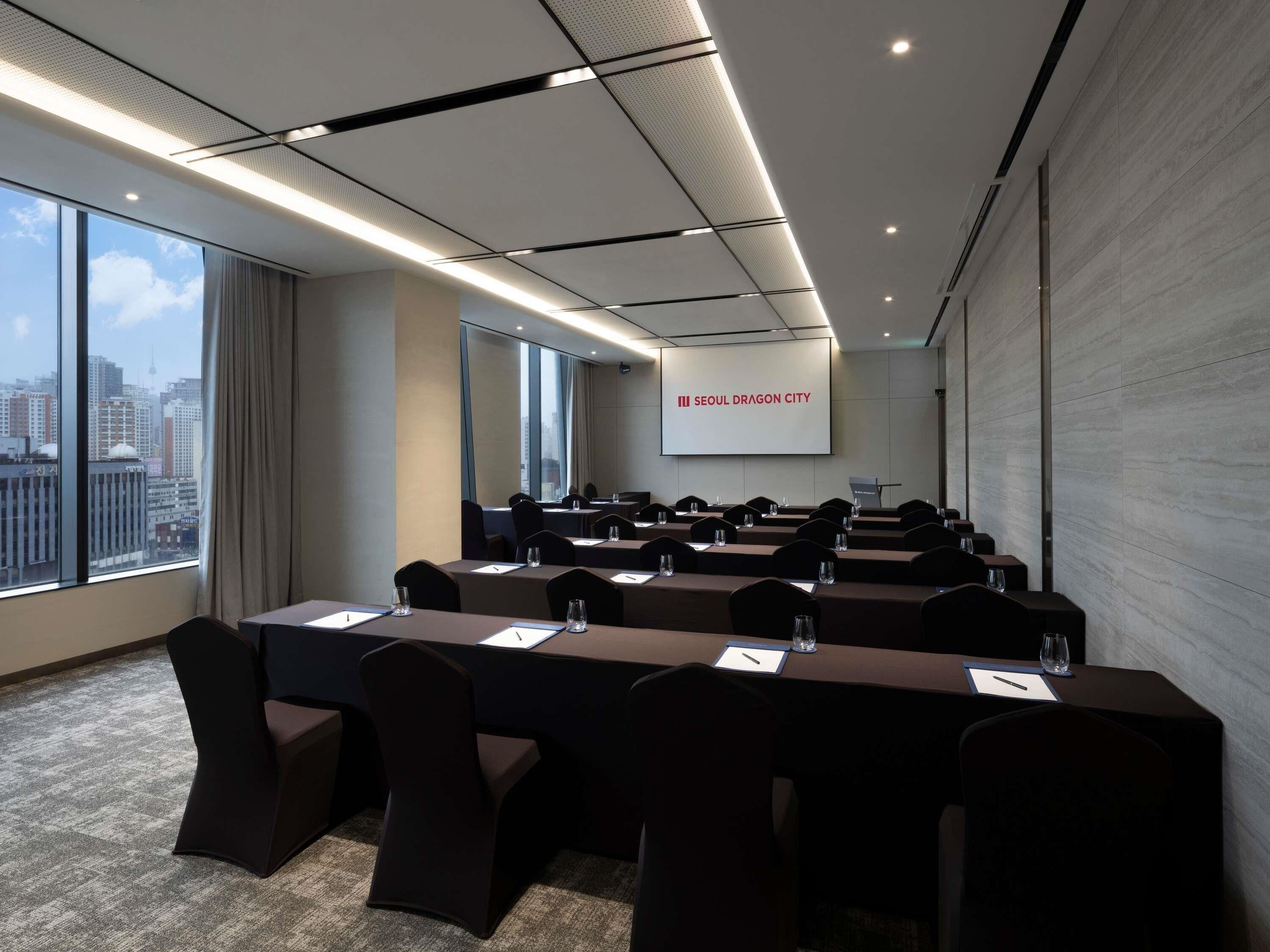 A conference room with a city view, large windows, and a presentation screen.