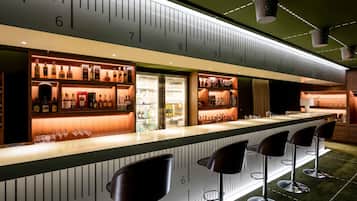 A bar area with a counter, stools, and shelves of bottles.