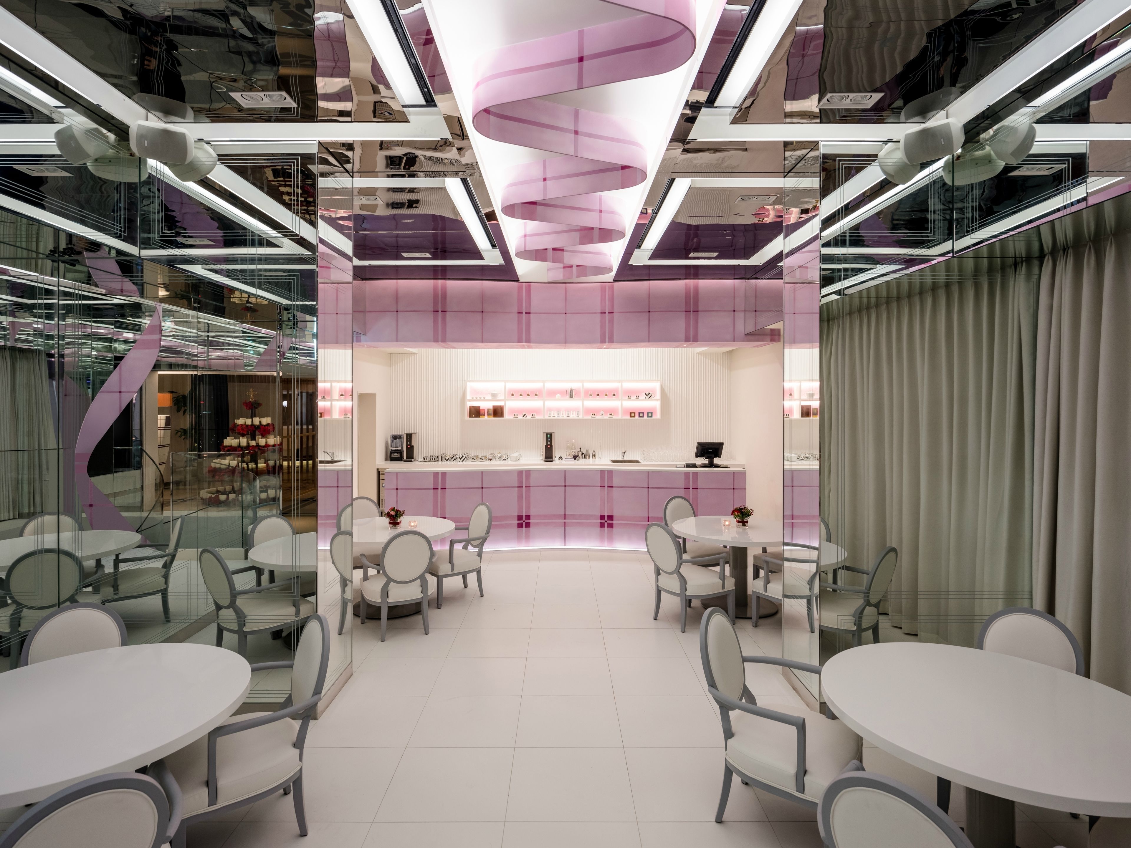 Un interior moderno con una zona de bar central, paredes de vidrio y mobiliario contemporáneo.