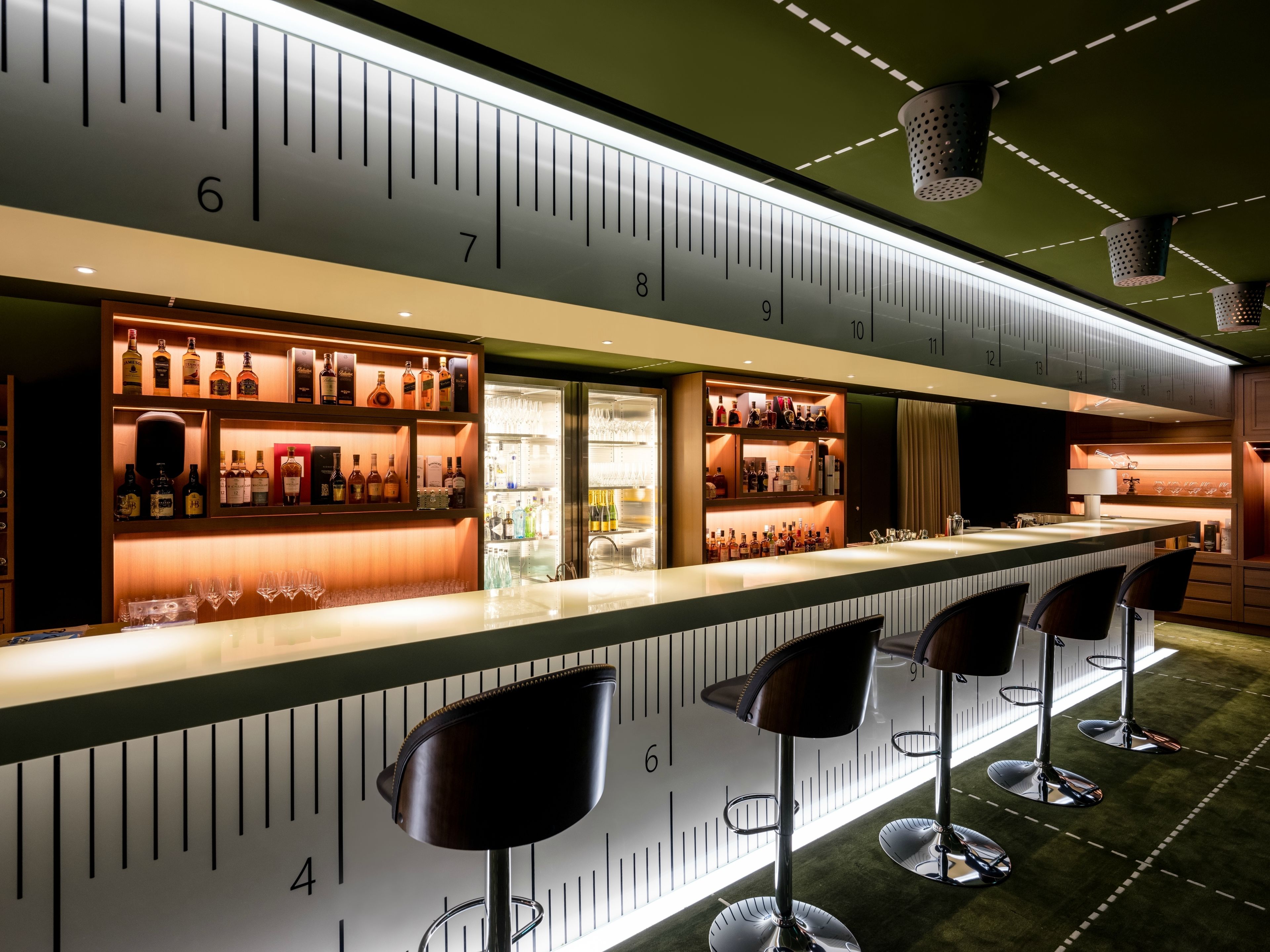 A bar area with a counter, stools, and shelves of bottles.