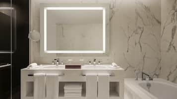 A modern bathroom with two sinks, a large mirror, and a bathtub.