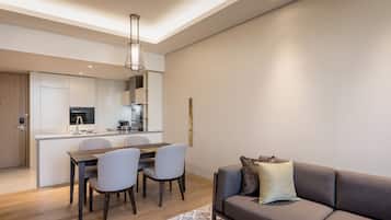 A modern living room with a sofa, a dining table with chairs, a kitchen area, and a pendant light.