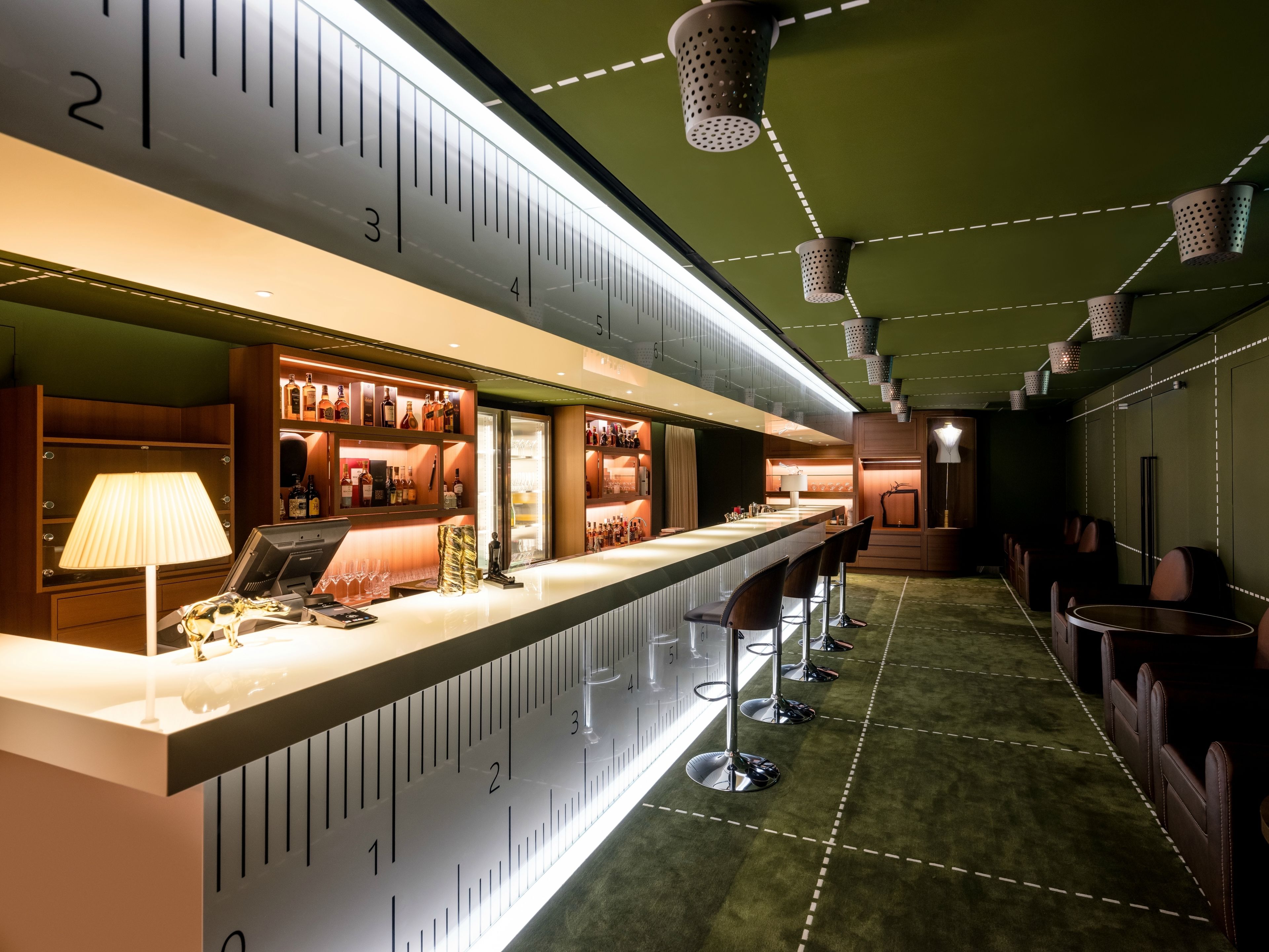 A bar area with a counter, stools, and shelves of bottles.