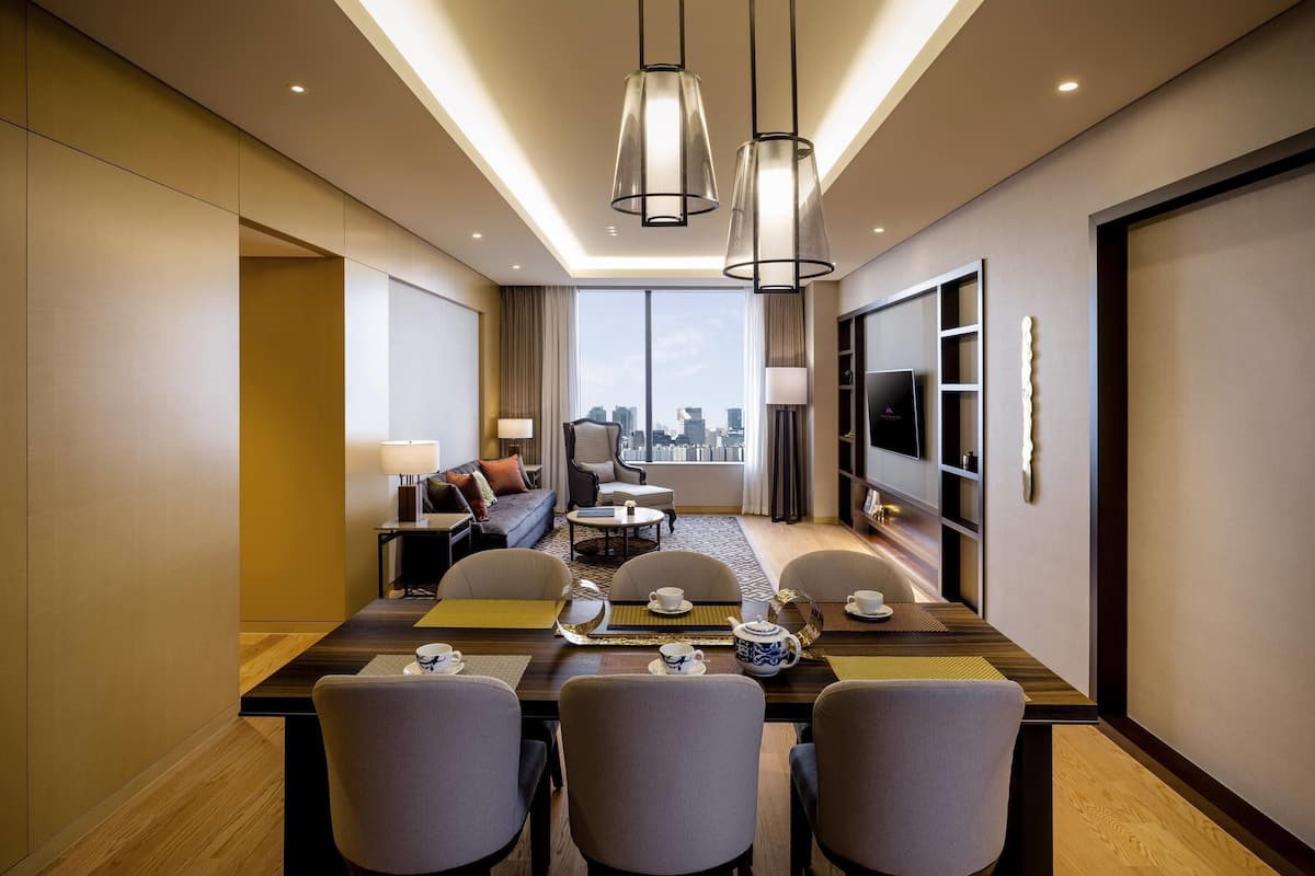 Une chambre d’hôtel moderne dotée d’un coin repas, d’un canapé, d’une télévision et offrant une vue sur la ville.