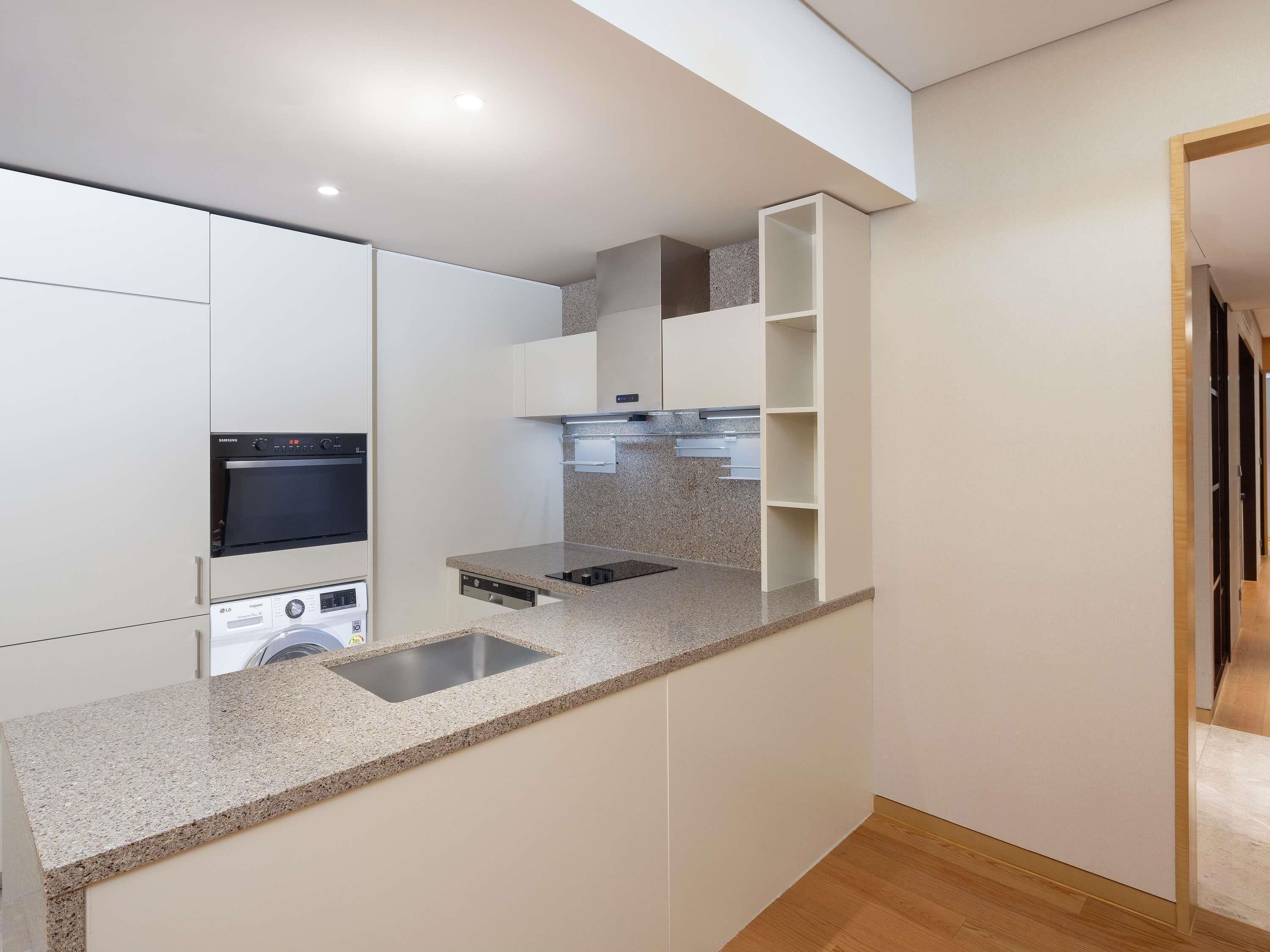 Una cocina moderna con electrodomésticos integrados, encimera de granito y suelo de madera.