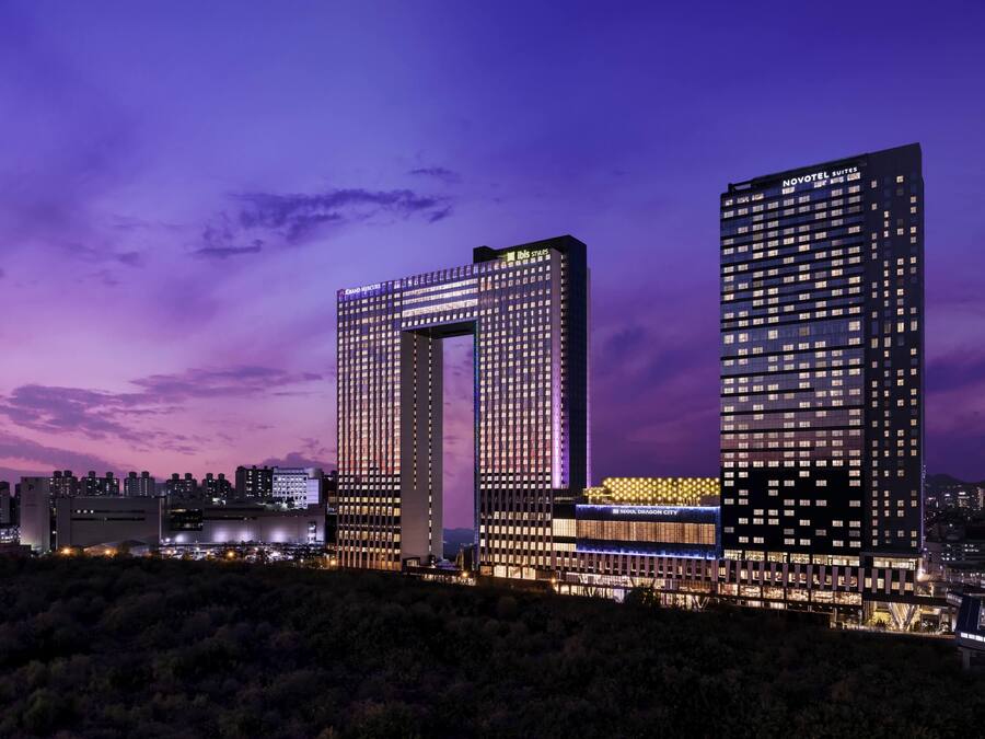 Zwei Hochhäuser mit beleuchteter Beschilderung, eines mit der Aufschrift 'Novotel Suites' und das andere mit 'Grand Mercure'.