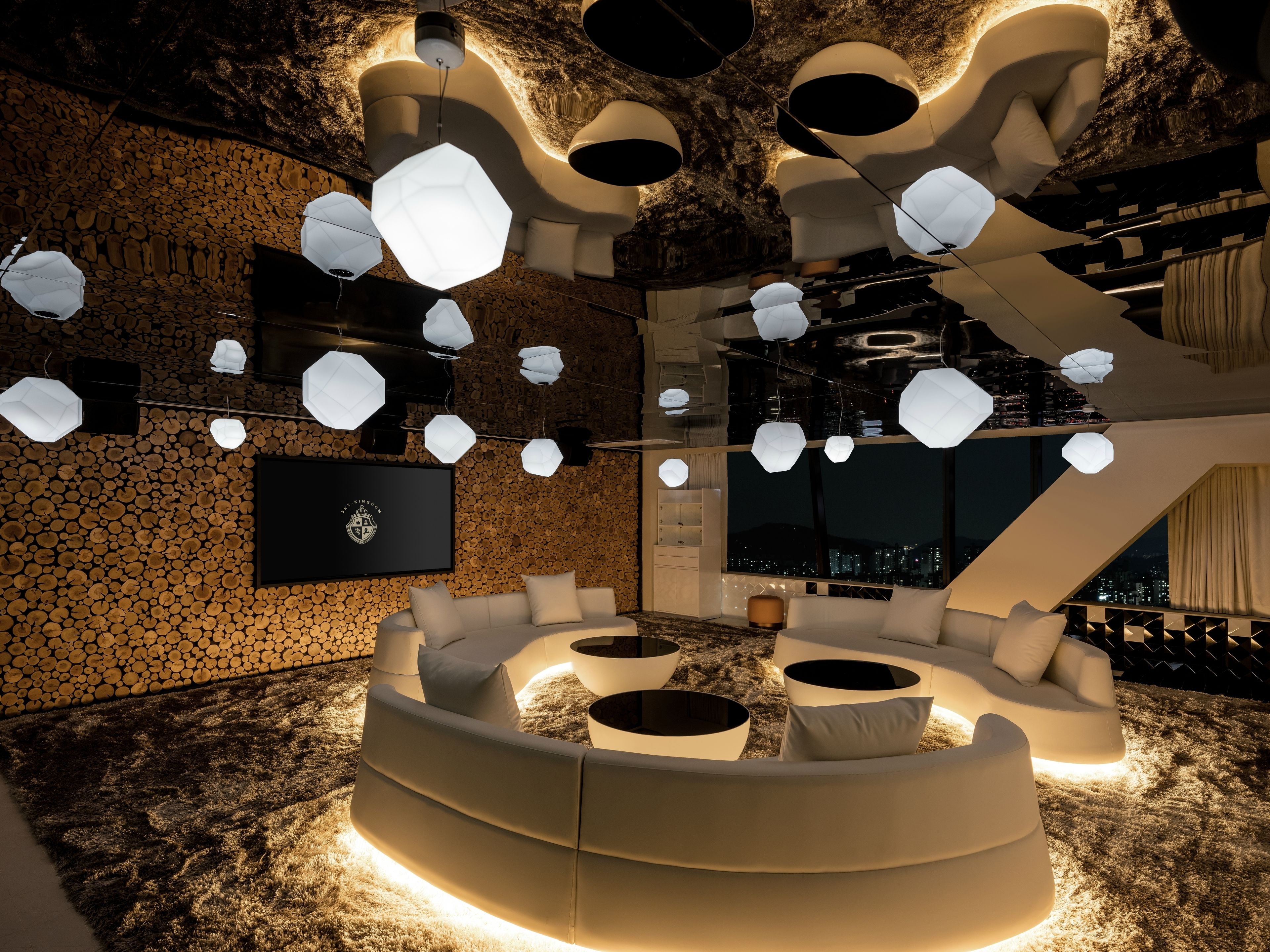 A modern interior with a curved seating area, multiple hanging light fixtures, and a city view through large windows.