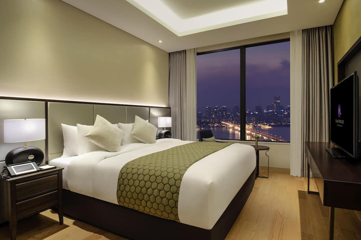Une chambre d’hôtel avec un grand lit, un bureau, une télévision et une vue sur la ville.