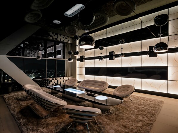 A modern lounge with a city view, sleek furniture, and ambient lighting.