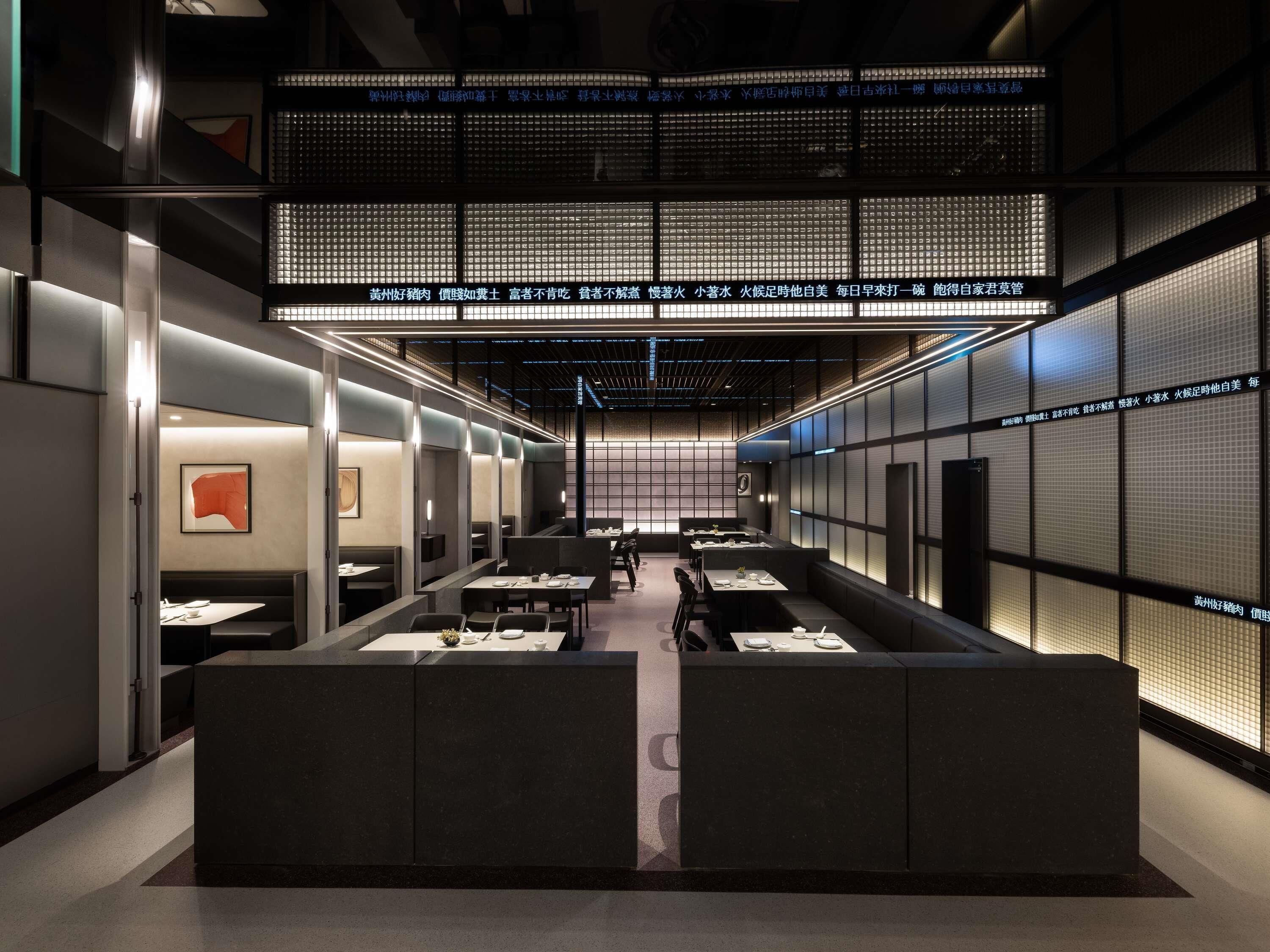 A modern restaurant interior with a central seating area, high ceilings, and a digital menu display.