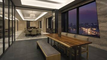 Un comedor moderno con una larga mesa de madera, bancos y vistas a la ciudad.
