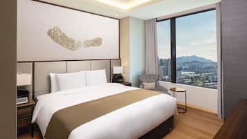 A modern hotel room with a large bed, a view of the city, and a decorative wall piece.