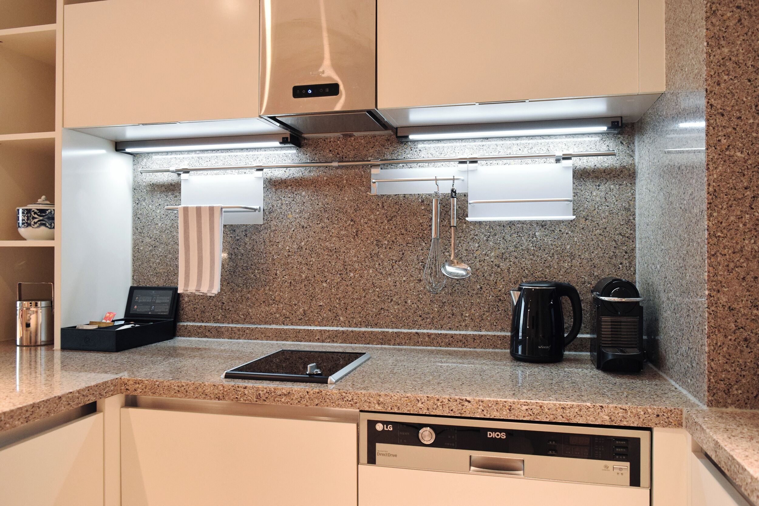A modern kitchen with a built-in dishwasher, a coffee maker, and a kettle.