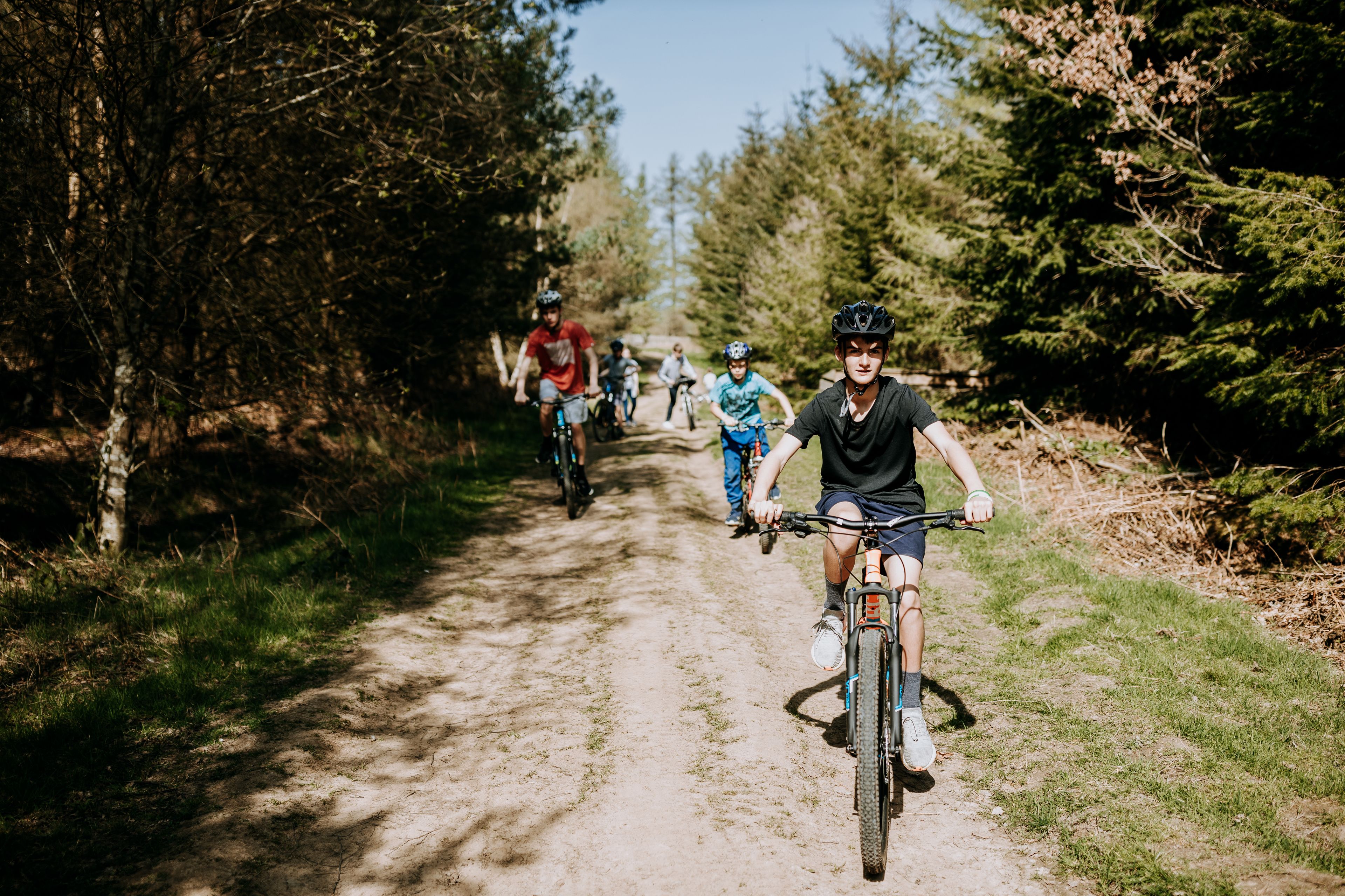 Een groep fietsers op een onverhard pad, omgeven door bomen.