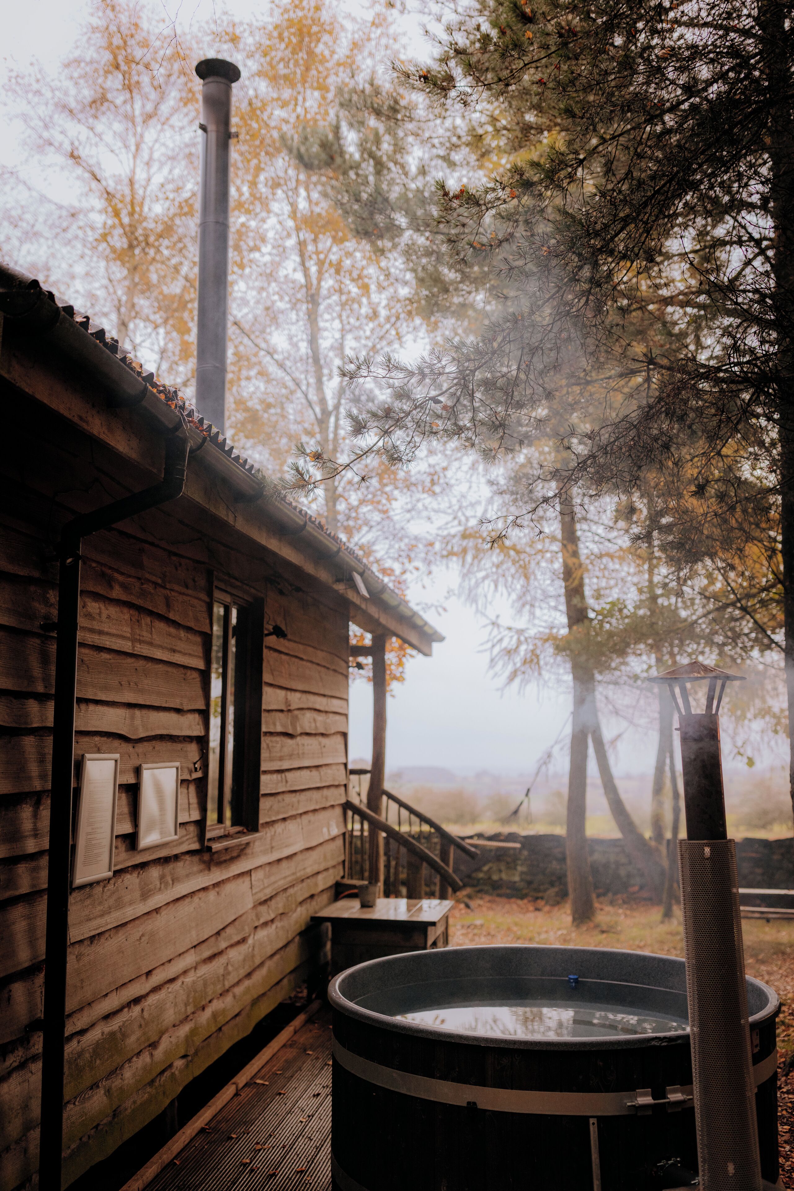 A rustic cabin with a hot tub and a chimney.