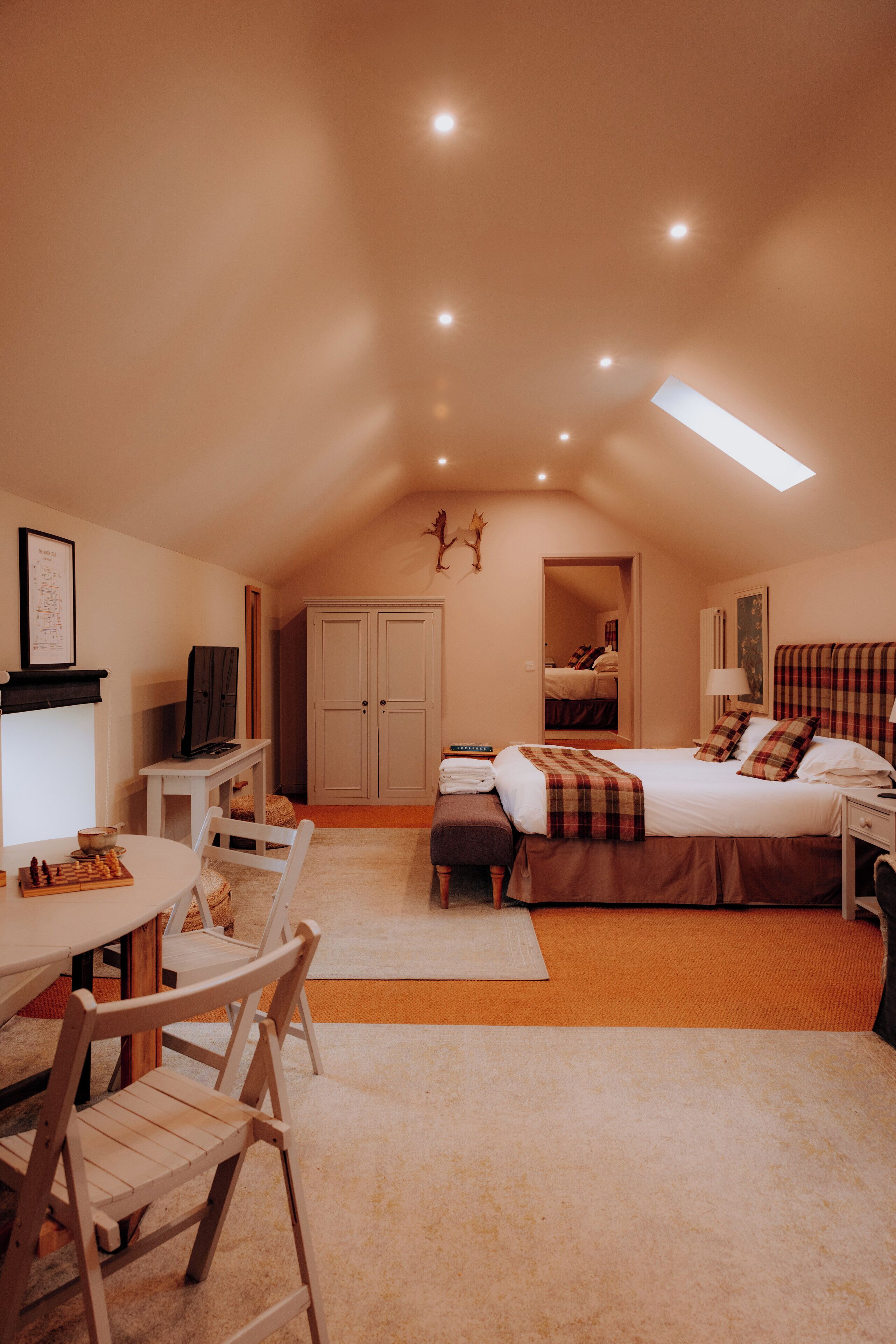Een gezellige slaapkamer met een bed, nachtkastjes, een bureau en een stoel. Uitzicht op een kledingkast en een deur die naar een andere kamer leidt.