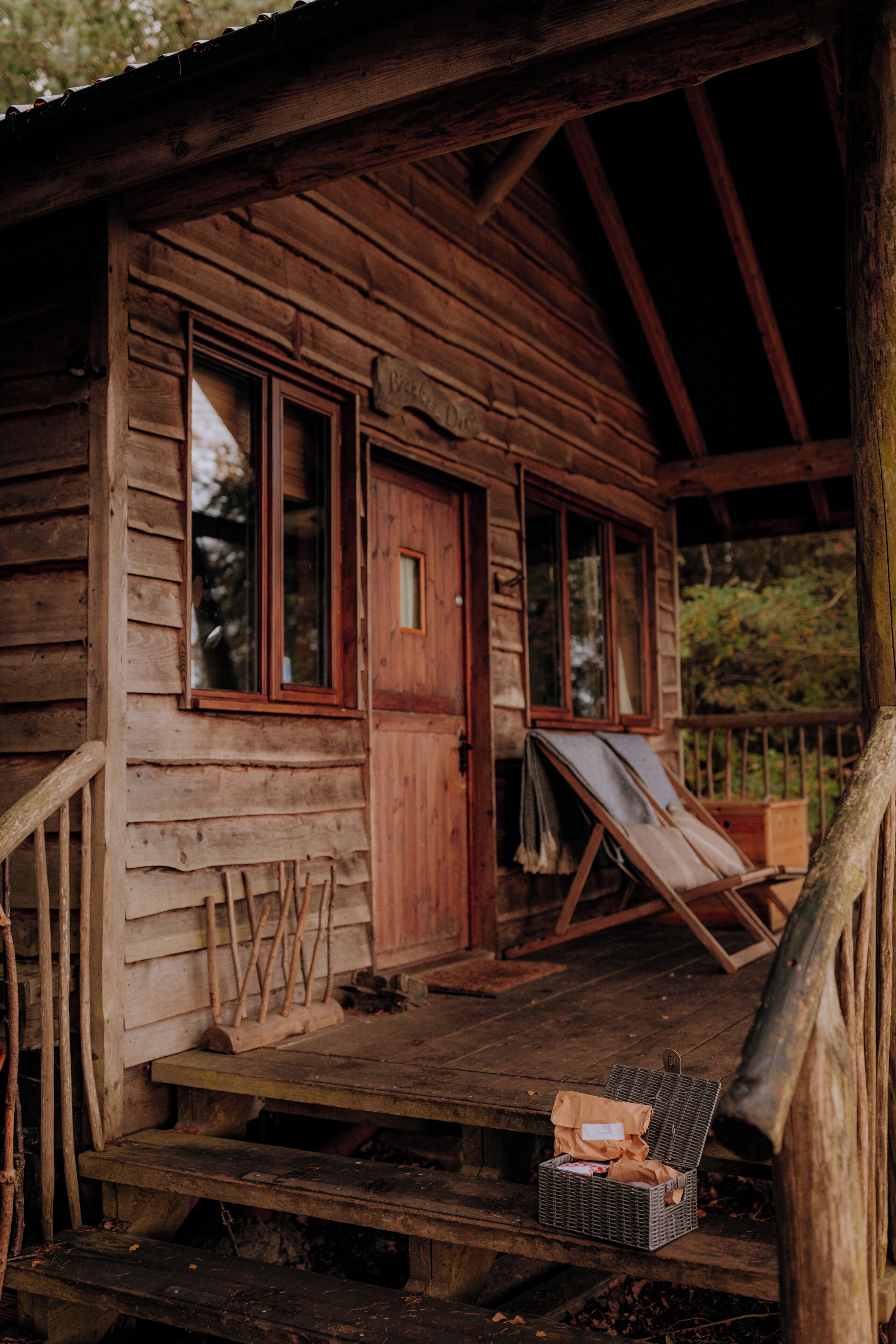A rustic wooden cabin with a porch, a door, and a window.