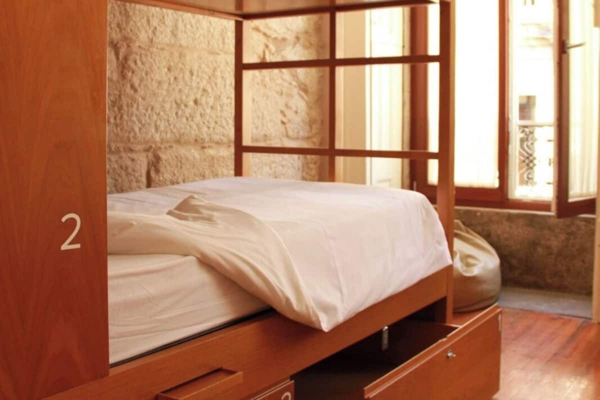 A bunk bed with two drawers and a window in the background.