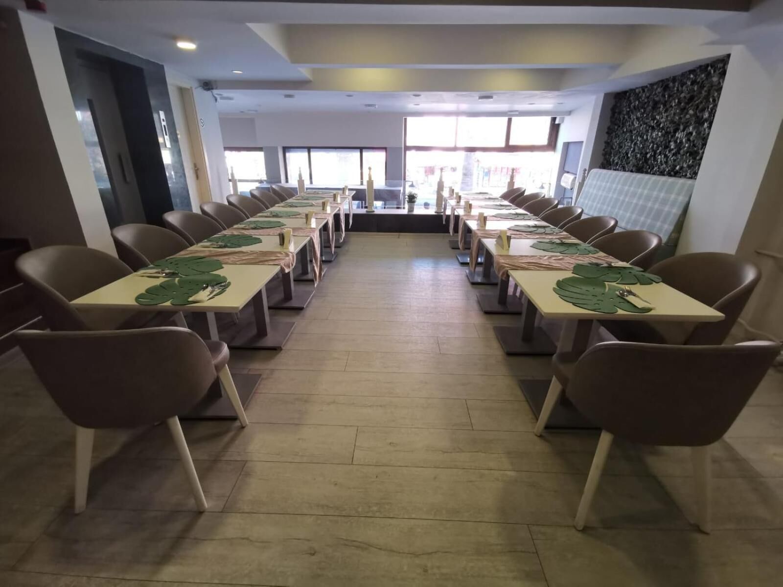 Une salle de conférence avec de longues tables et des chaises, de grandes fenêtres et un mur en pierre.