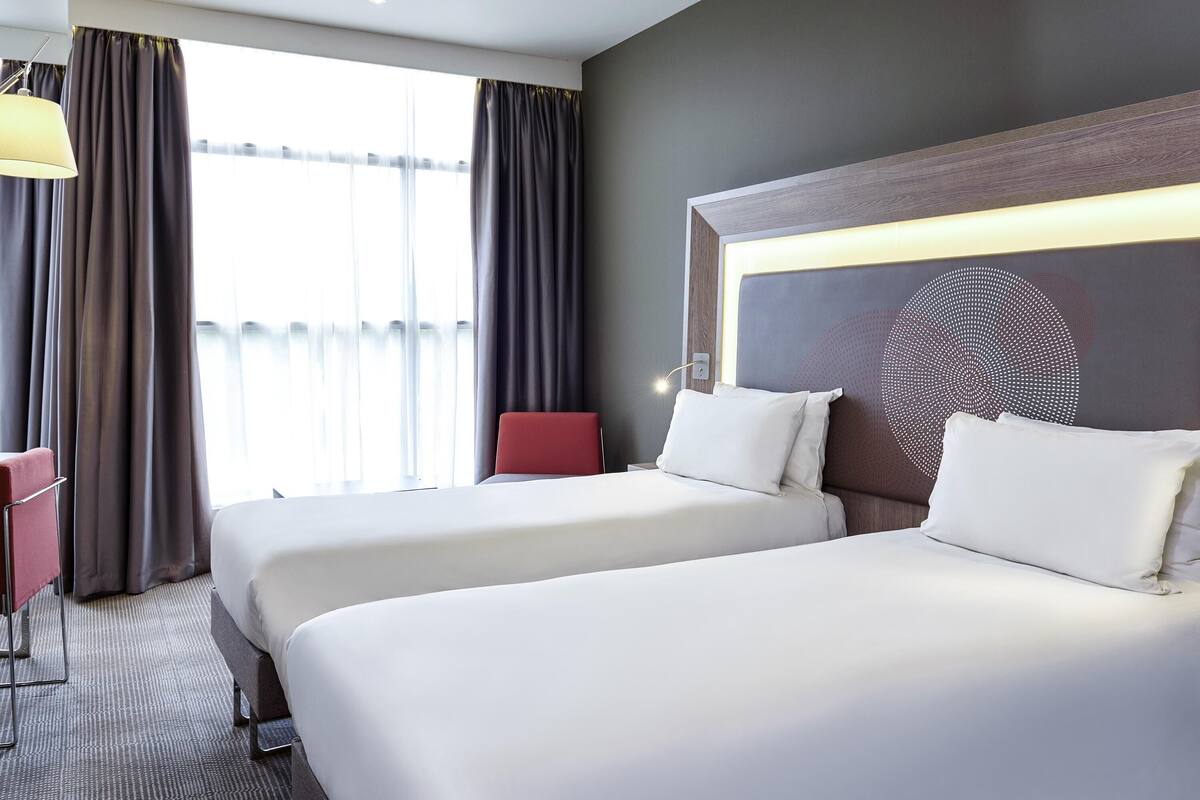 Une chambre d’hôtel avec deux lits, un bureau et une chaise.