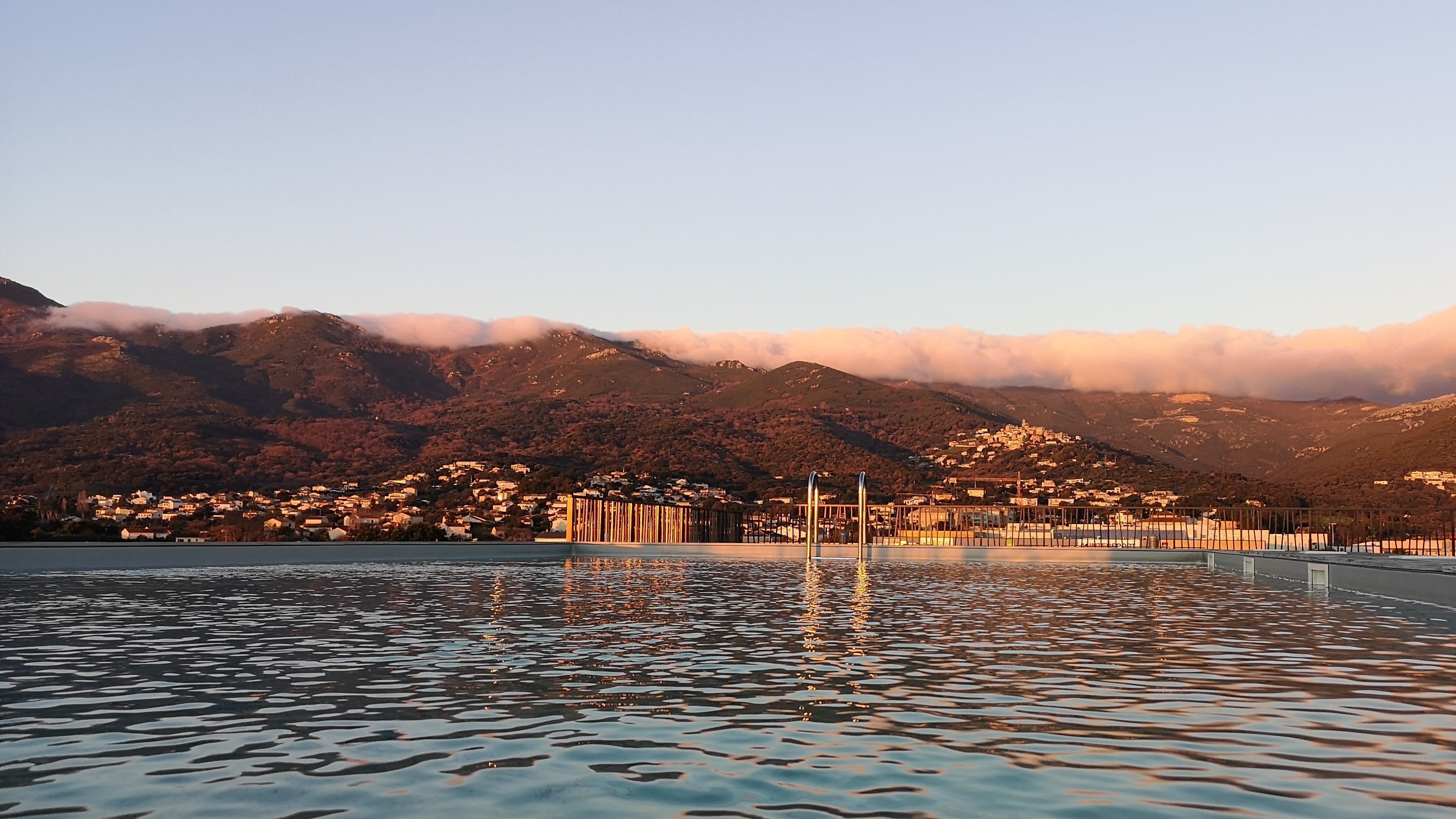 Una piscina con montañas al fondo y un pueblo.