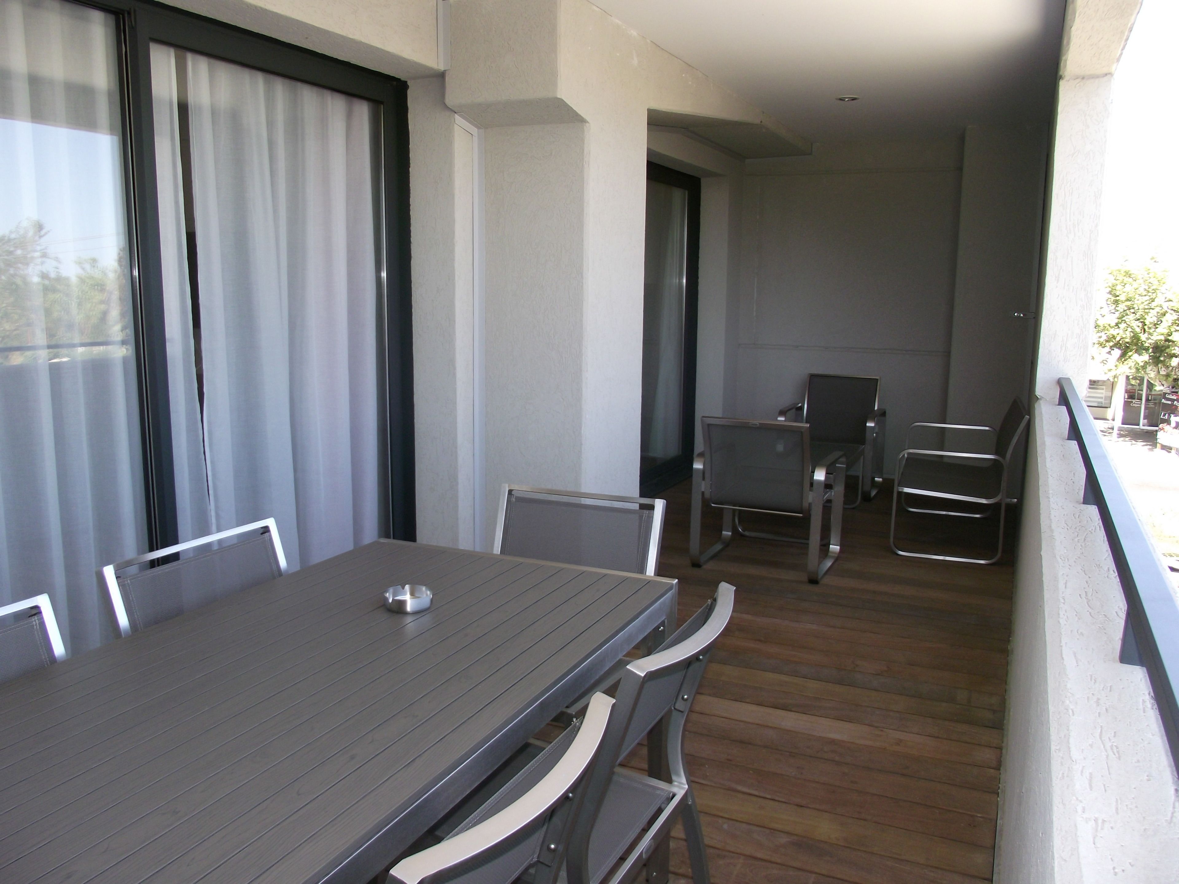 A balcony with a dining table and chairs, a small seating area, and a view of the outside.
