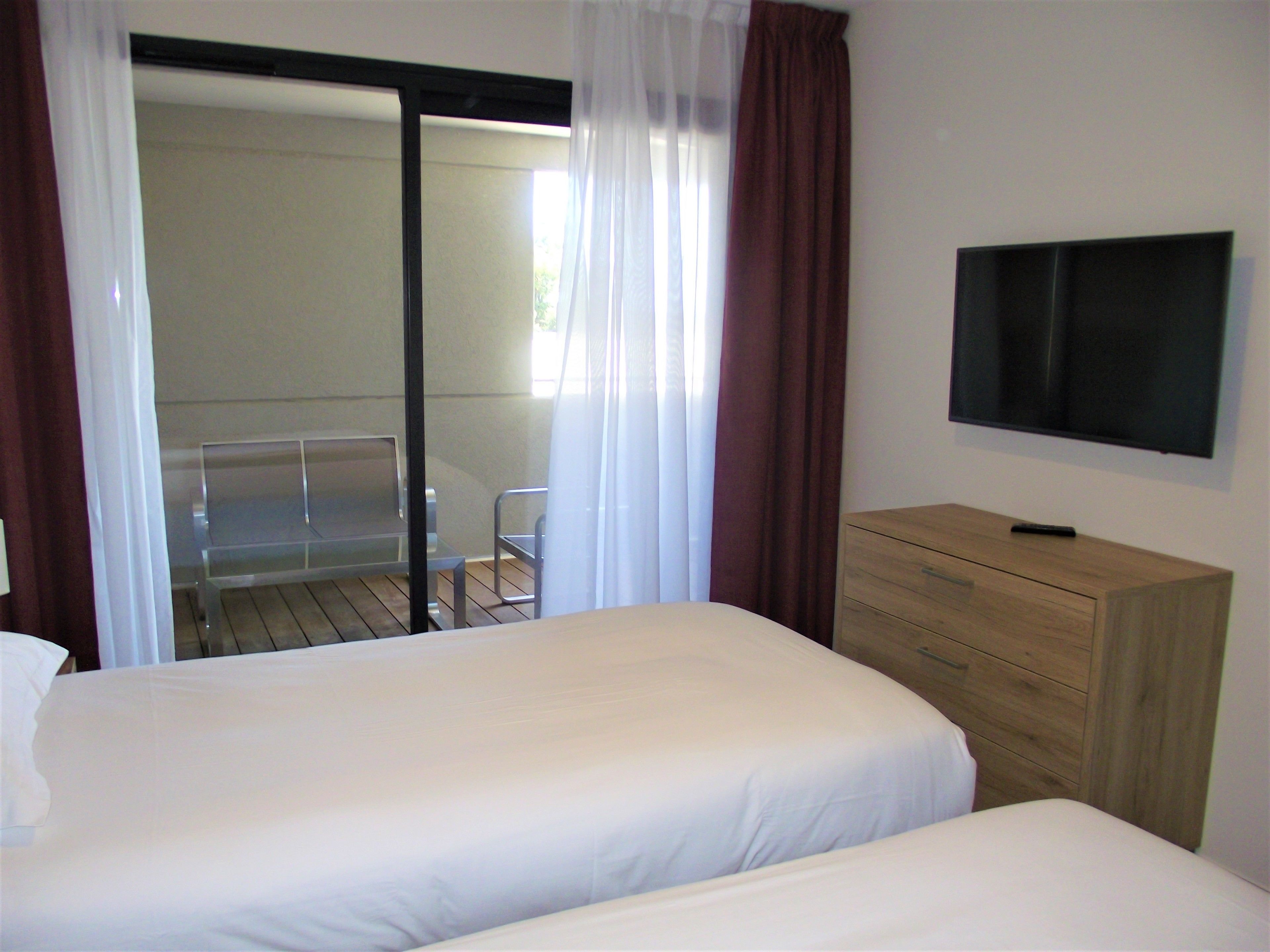A hotel room with two beds, a TV, and a wooden dresser.