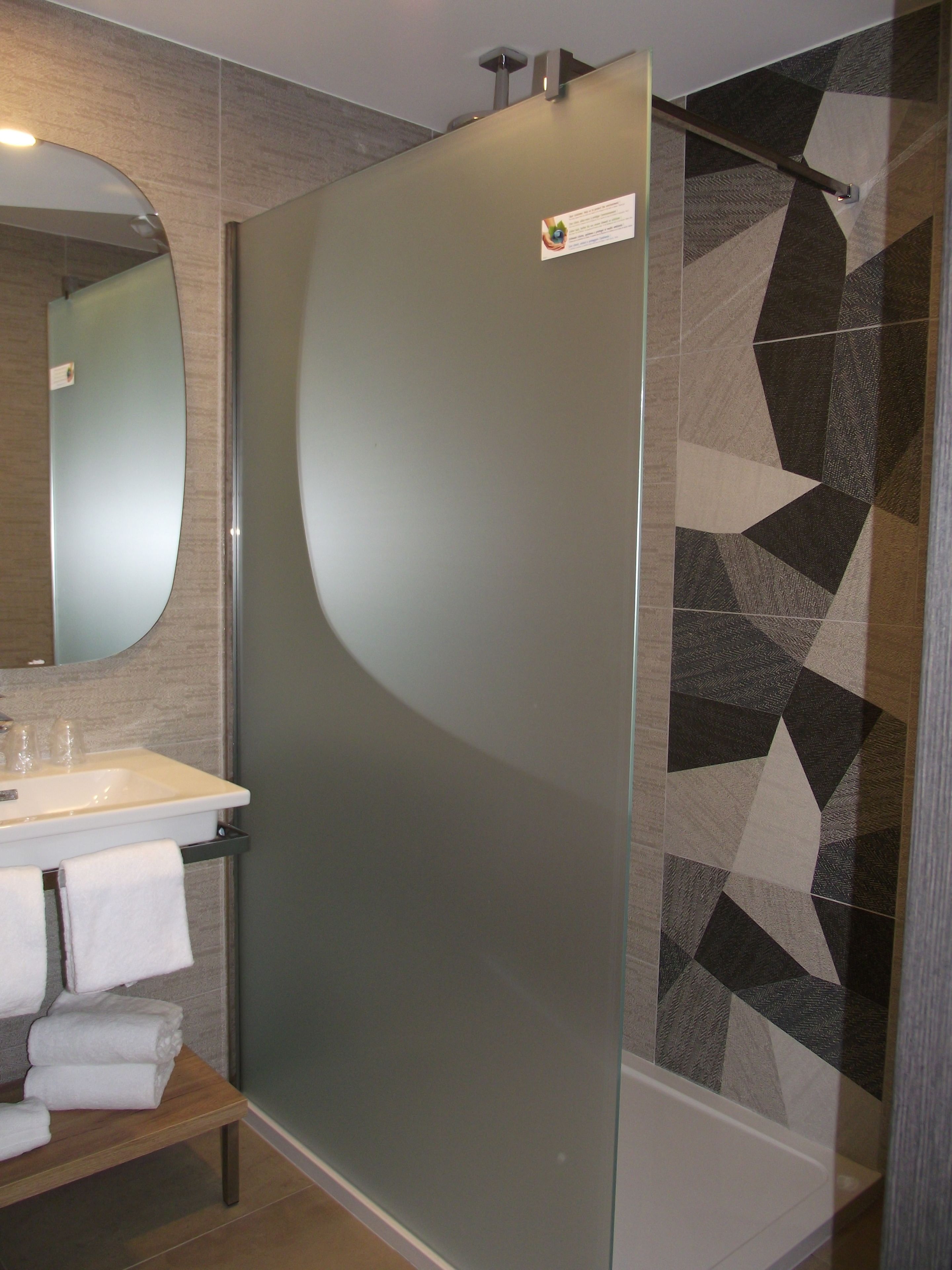 A bathroom with a glass shower enclosure, a sink with a mirror, and a towel rack.