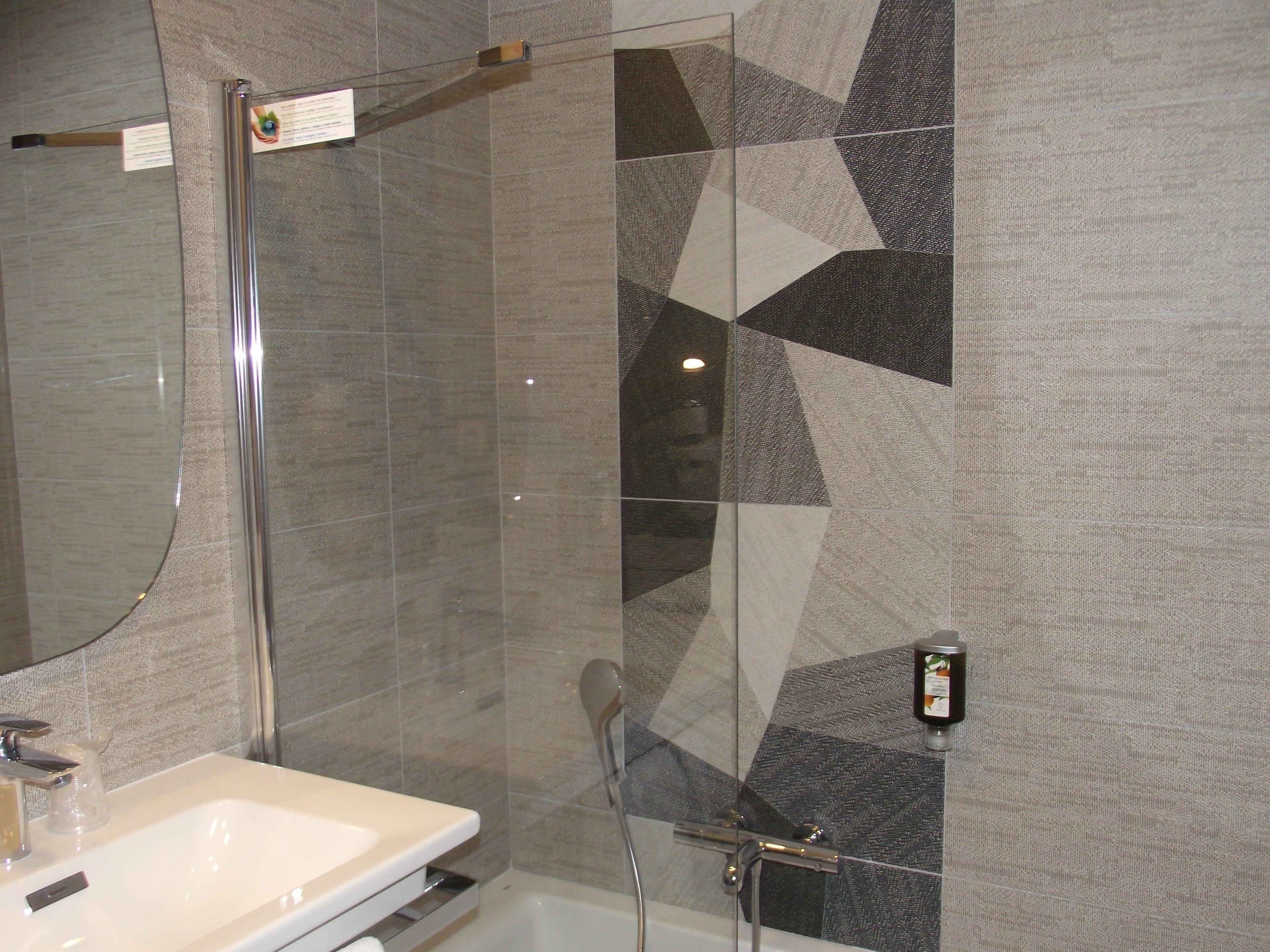 A bathroom with a shower, a sink, and a mirror.