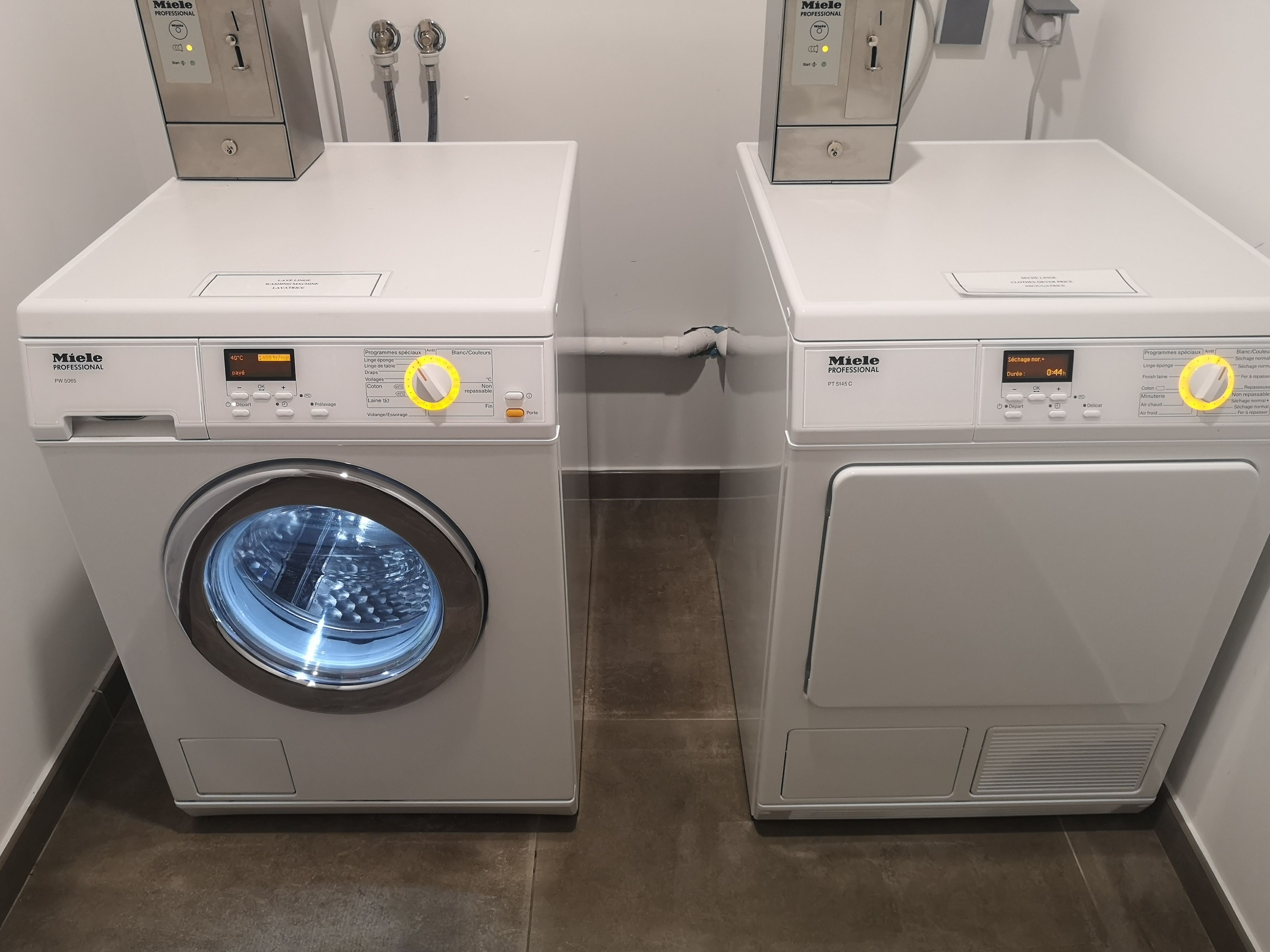 Twee Miele Professional wasmachines naast elkaar in een wasserij.