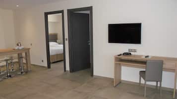 Ein Hotelzimmer mit einem Bett, einem Schreibtisch mit Stuhl, einem Fernseher und einer Minibar.