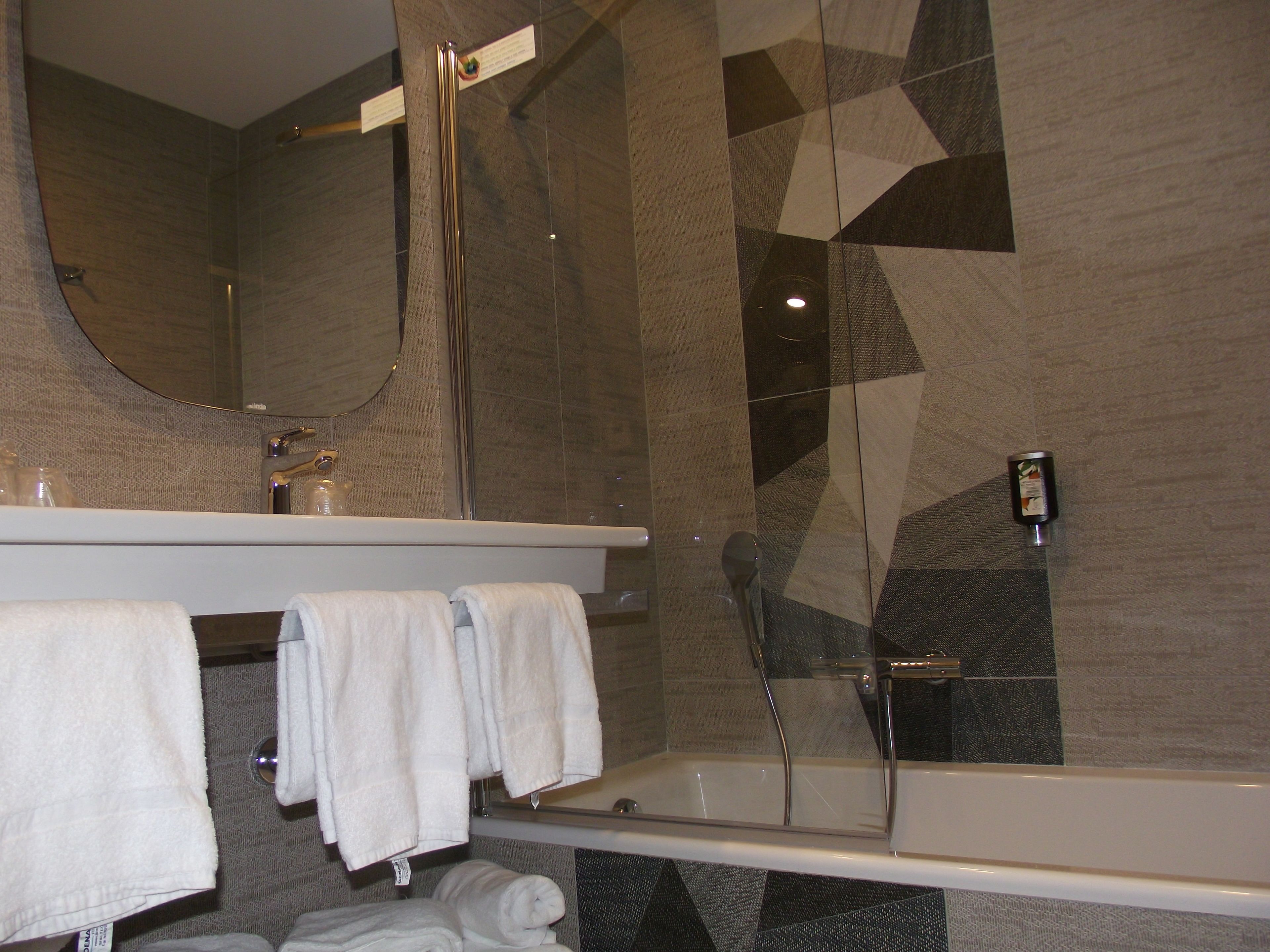 A modern bathroom with a bathtub, a mirror, and a towel rack.