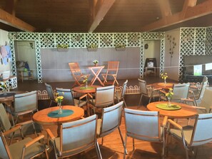 A dining area with wooden tables and chairs, some with flower vases. - Auberge La Coudriere-Cool Hotel (Isle aux Coudres)