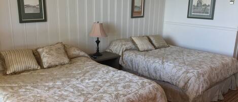 Une chambre d’hôtel avec deux lits, une table de chevet avec une lampe et des tableaux encadrés aux murs.