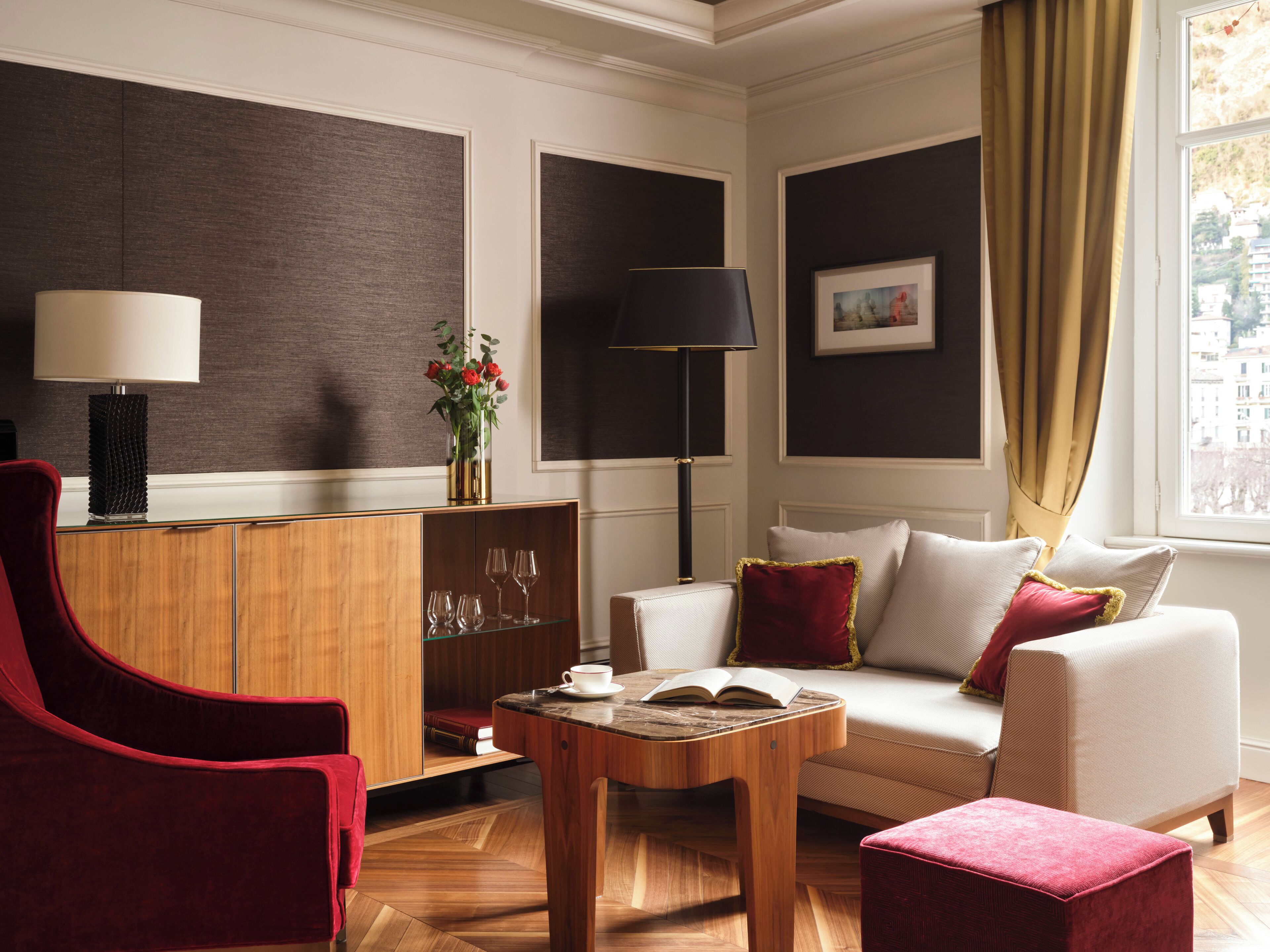 A modern living room with a red armchair, a white sofa, a wooden coffee table, and a bookshelf.