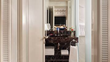 A modern bathroom with a marble sink, a glass shower enclosure, and a towel rack.
