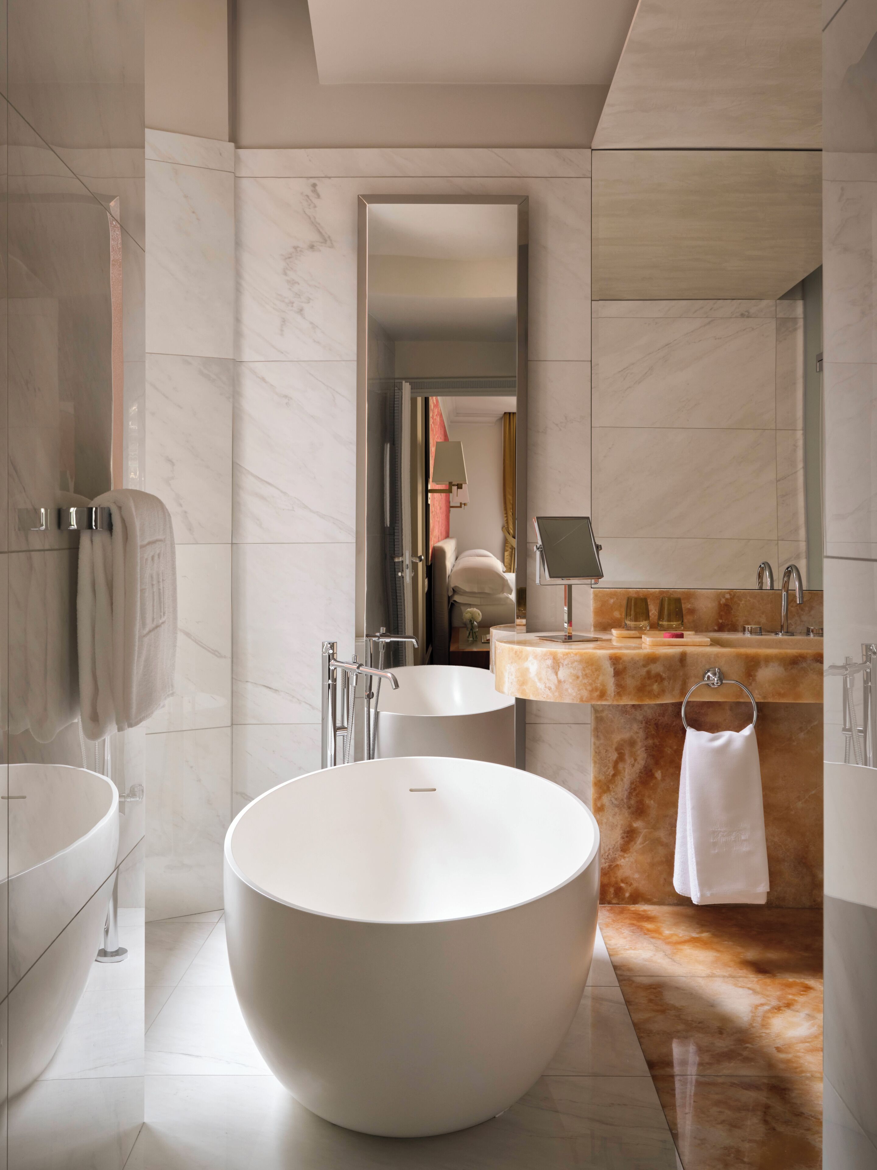 Un baño moderno con una bañera independiente grande, un lavabo y un tocador con espejo.