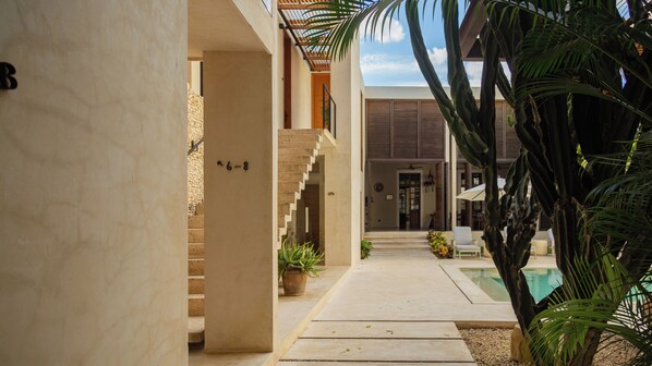 A modern building with a pool, a staircase, and potted plants.