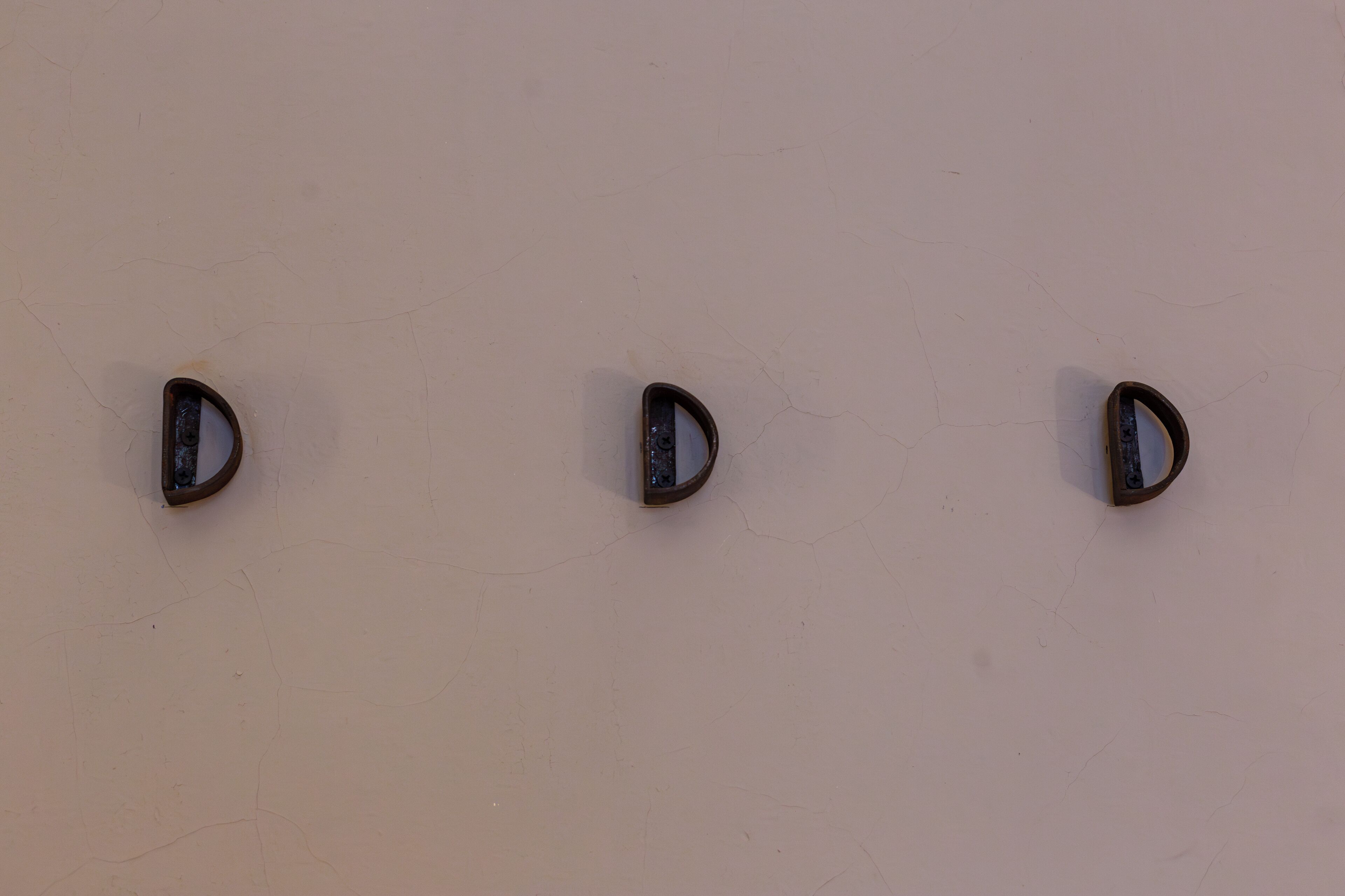Tres objetos fijados a la pared sobre un fondo liso.