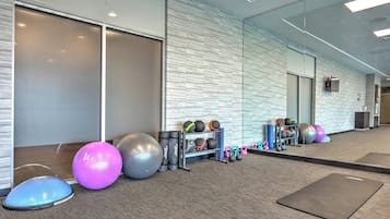 A gym with exercise equipment, mats, and a mirrored wall.