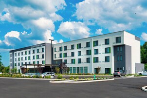 Un hotel Courtyard Marriott con diseño moderno, que cuenta con un estacionamiento y una zona ajardinada con un hidrante.