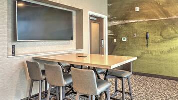 A conference room with a large table, four chairs, a projector screen, and a door.