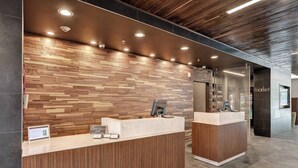 Zona de recepción con pared de madera y dos mostradores, cada uno con un monitor de computadora y un letrero que indica membresía.