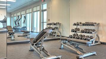 A gym with cardio machines, dumbbells, and a mirror.