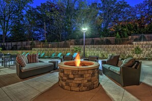 An outdoor patio area with a stone fire pit, wicker furniture, and lounge chairs. - Residence Inn by Marriott Blacksburg-University (Blacksburg)