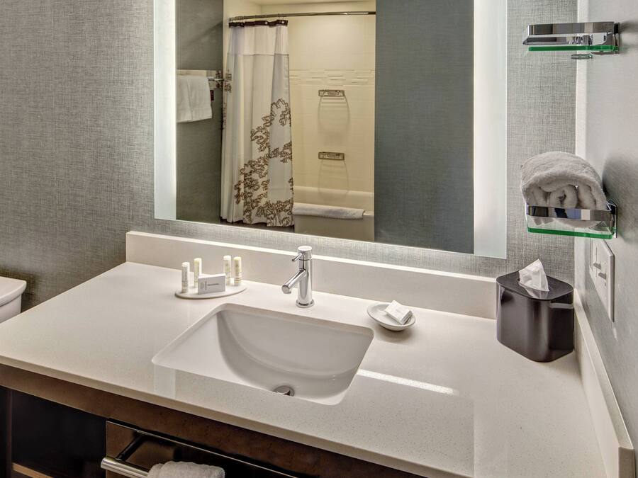 A modern bathroom with a white sink, a mirror, and a towel rack.