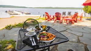 A dining table with a meal, outdoor chairs, and a lake view. - Gunflint Lodge & Outfitters (Grand Marais)